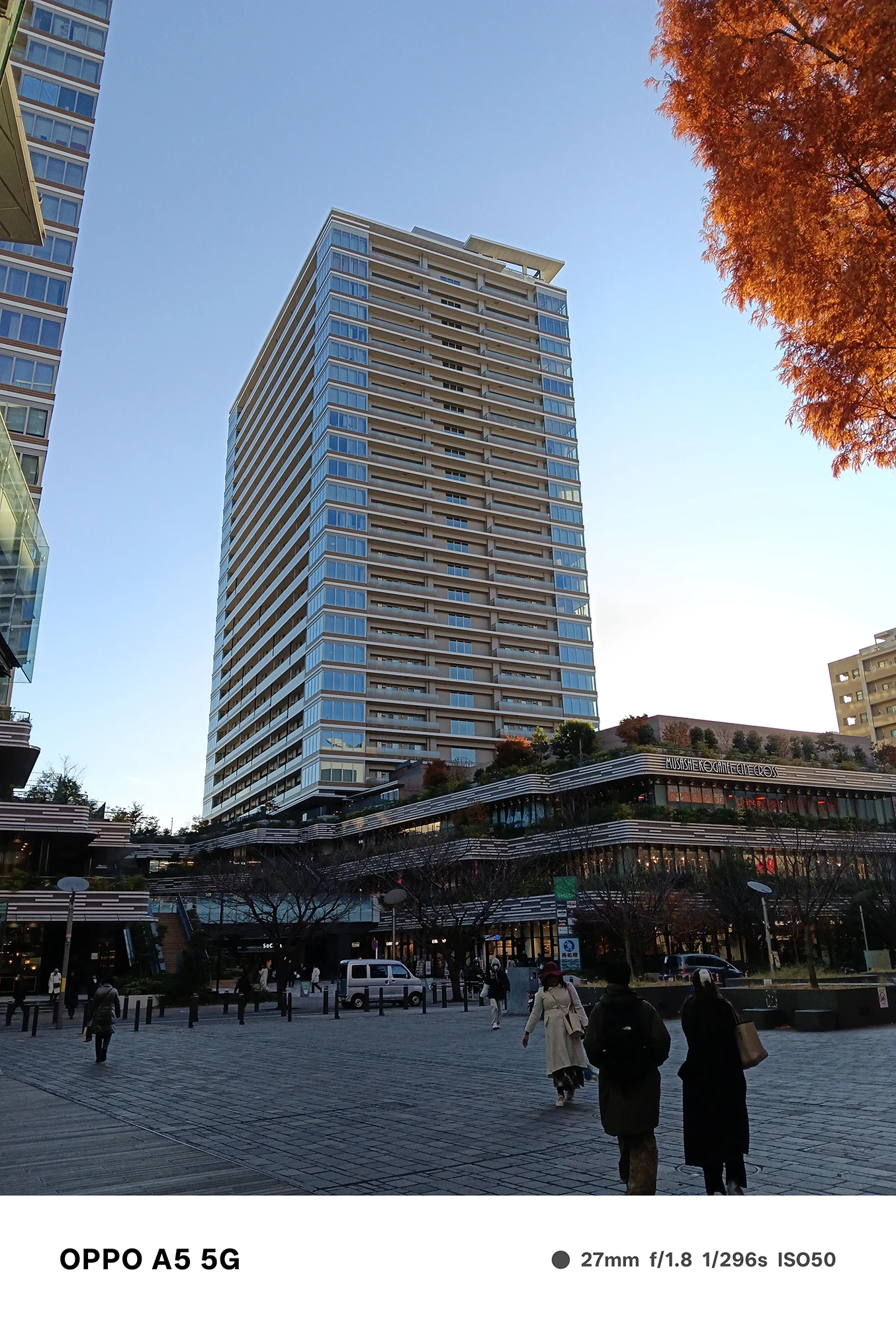 OPPO A5 5Gで撮影した都市部の高層ビル。澄んだ青空とビルのガラス反射、街路の人の動きがクリアに写る夕方の都市景観