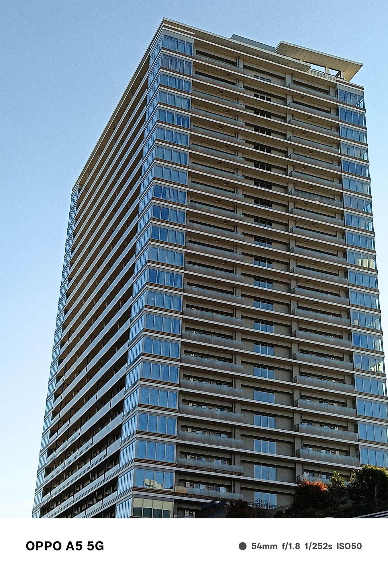 OPPO A5 5Gで撮影した高層マンションの外観。青空を背景に、窓の反射と建物のディテールをシャープに描いた建築写真