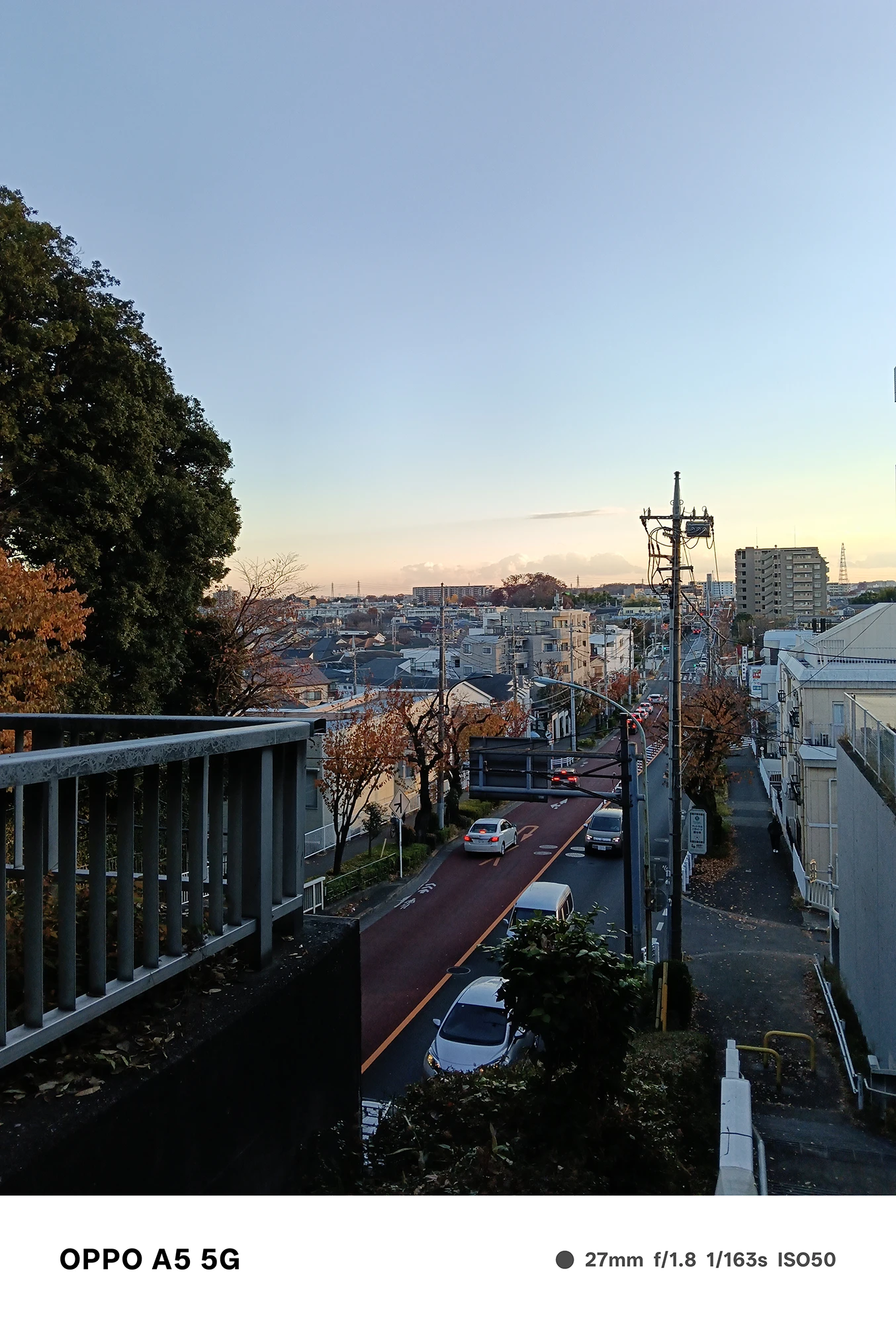 OPPO A5 5Gで撮影した夕方の住宅街の遠景。赤く染まった道路と建物が連なる街並みを、高台から広角で鮮明に捉えた風景写真