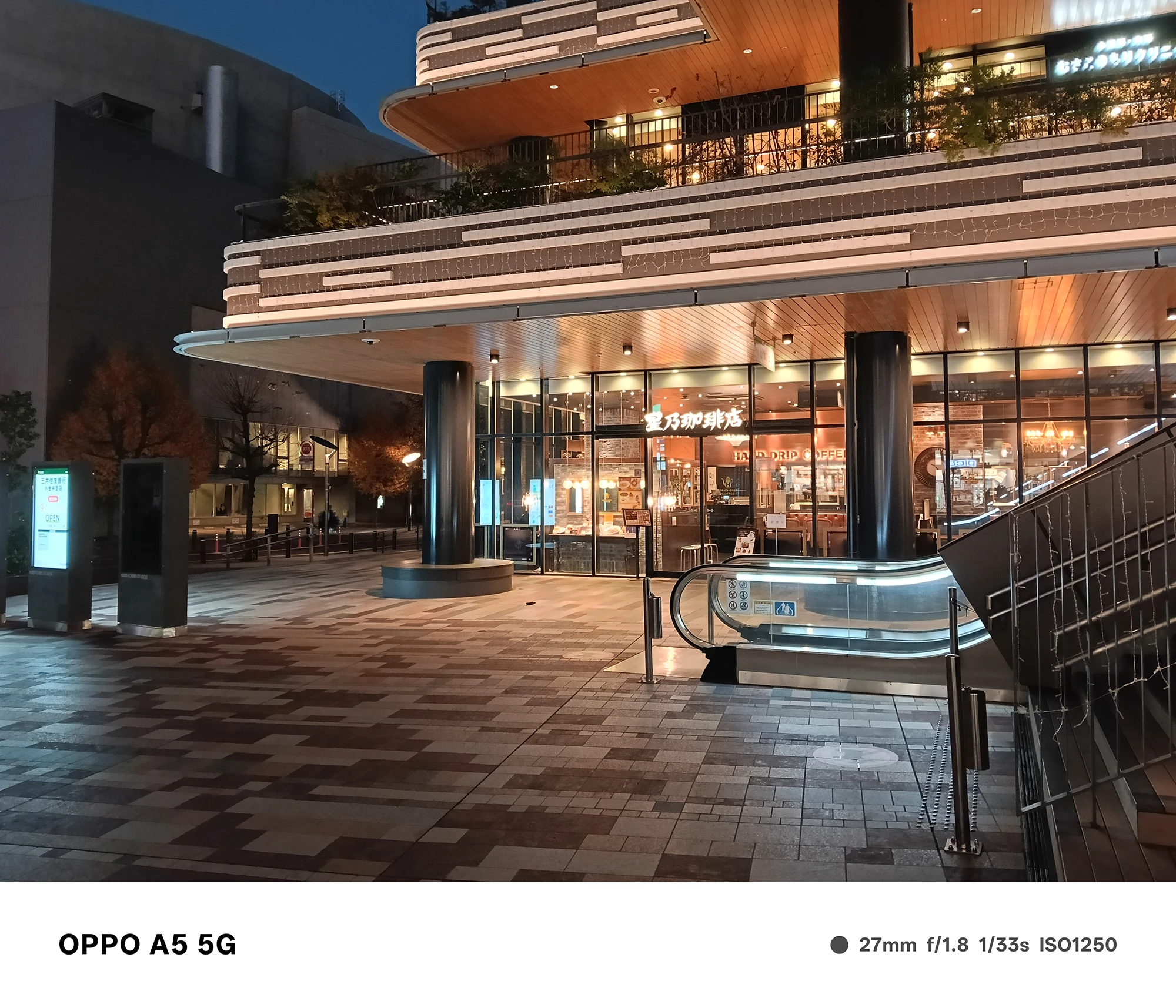 OPPO A5 5Gで撮影した星乃珈琲店付近の夜景。店舗の暖色照明とエスカレーター、建物の重厚な外観を鮮明に写した作例