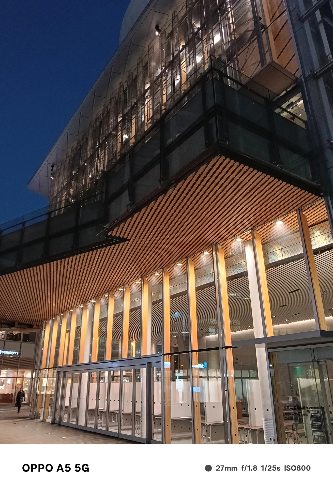 OPPO A5 5Gで撮影した近代建築の外観。木製ルーバーとガラス壁面がライトアップされ、建物の質感と透明感を美しく描いた夜景