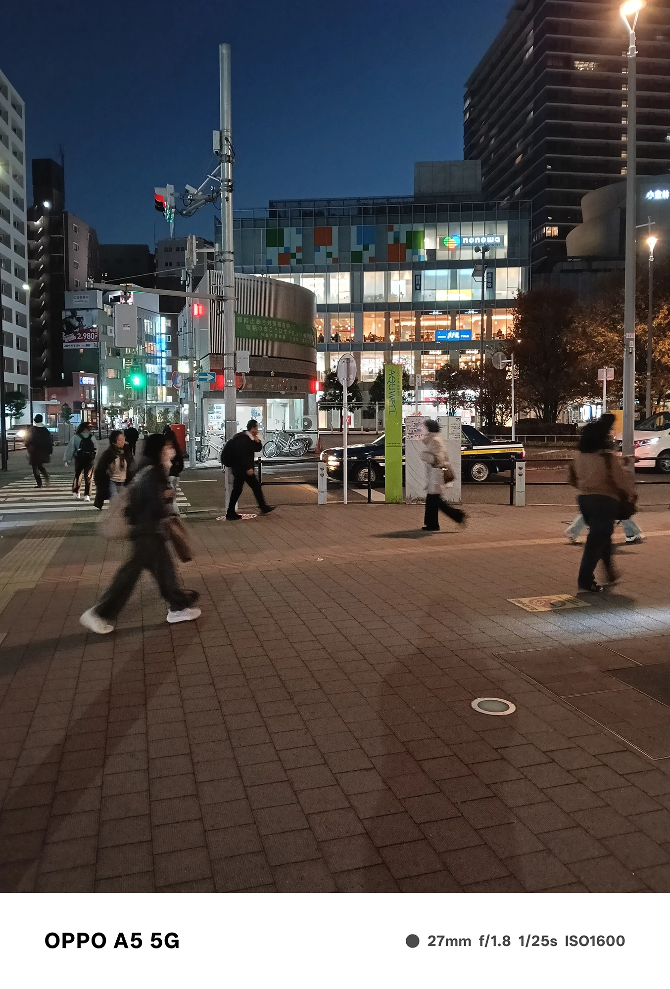 OPPO A5 5Gで撮影した駅前交差点の夜景。歩行者の動きとビルの光、信号機の色彩を鮮明に捉えた都市スナップ