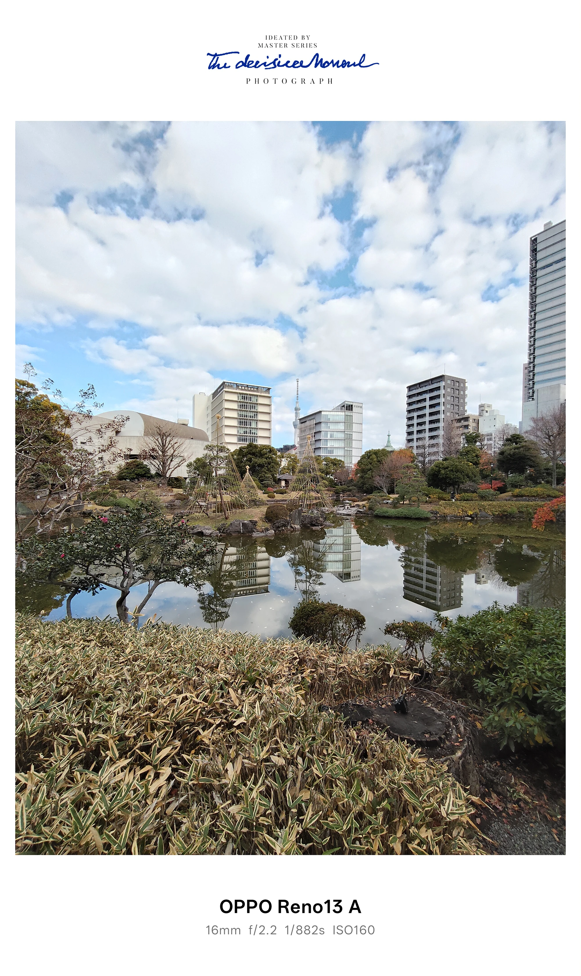OPPO Reno13 Aの超広角で撮影した庭園の池と雲の反射（周囲にビル群）