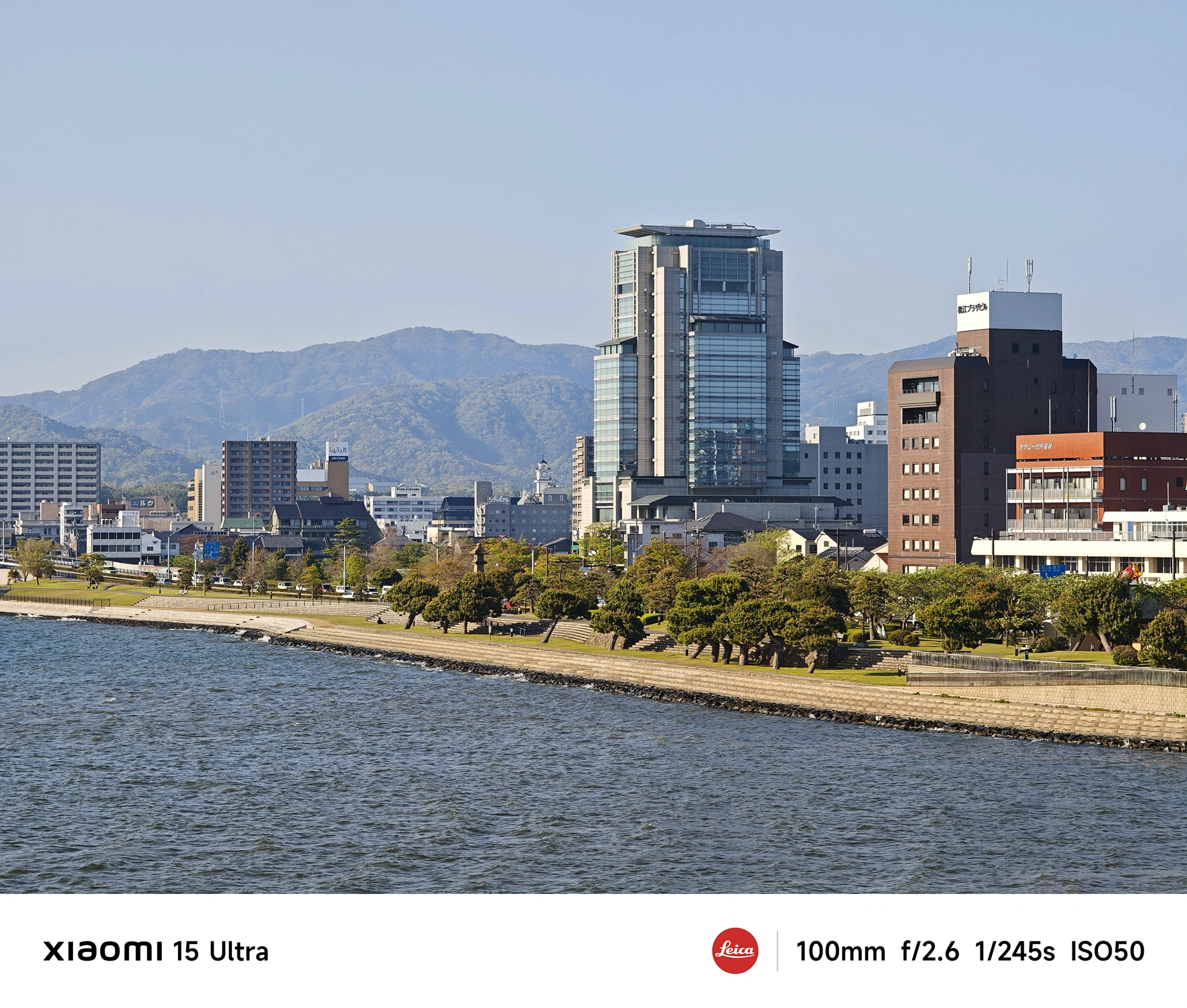 川沿いの街並みと高層ビル、背後の山並みまで見渡す望遠の風景写真(Xiaomi 15 Ultra/100mm)