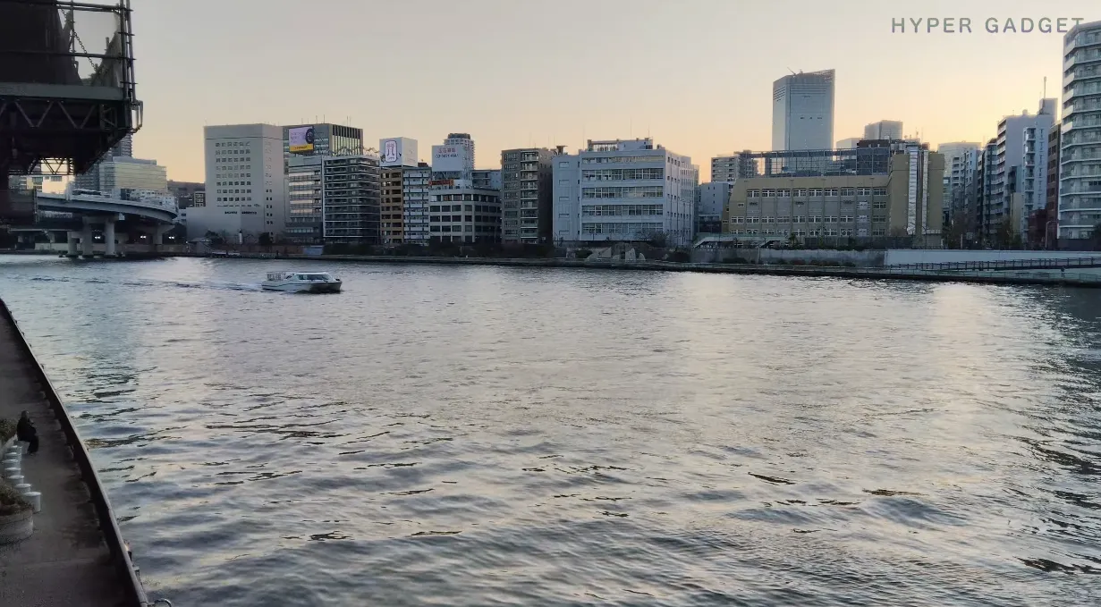 OPPO Reno13 A 昼景作例：川辺を航行する水上バスと高層ビル群を撮影（夕方の柔光）