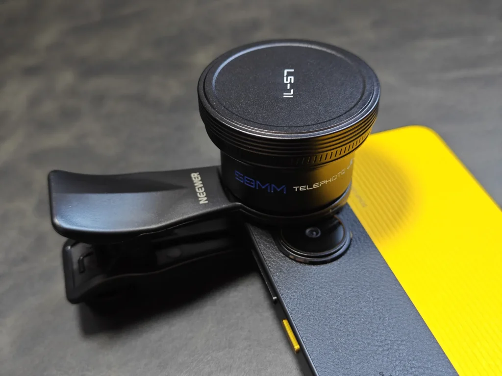 イエローカラーのPOCO X7 Pro背面に装着されたNEEWER LS-71 58mm望遠レンズ。レンズキャップを付けた状態の重厚なセットアップ。