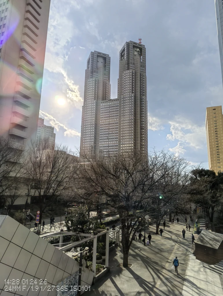 Nothing Phone (3a) Liteで撮影した、逆光の空にそびえる高層建築と光芒が写り込んだ都市風景