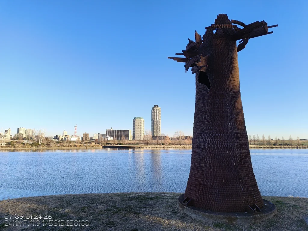 Nothing Phone (3a) Liteで撮影した、水辺に立つ彫刻と周囲の都市景観