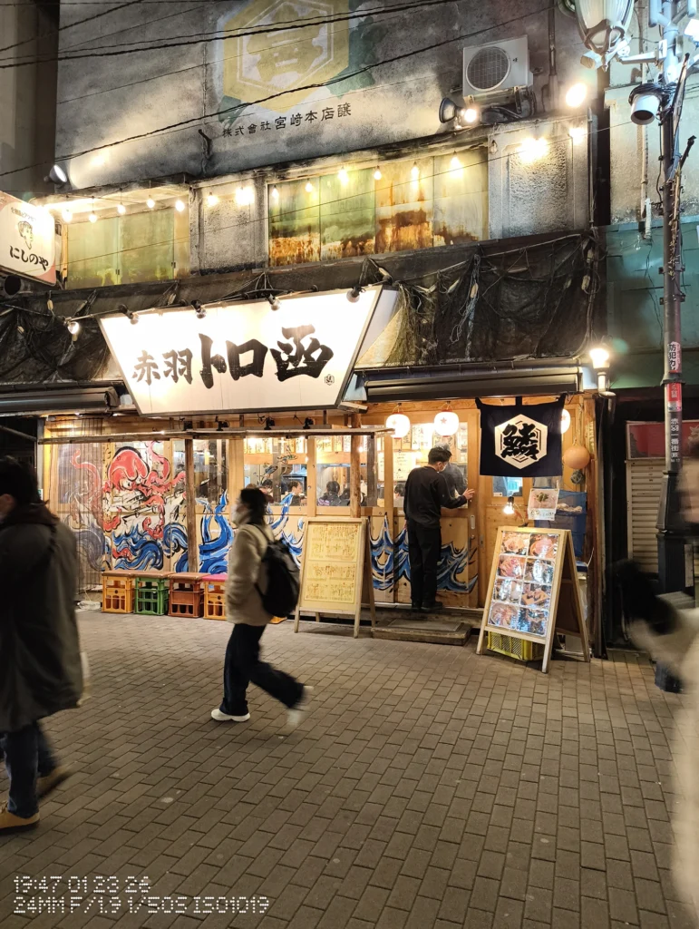 Nothing Phone (3a) Lite/カメラ:メイン(広角)/焦点距離:24mm相当/内容:提灯と電球の灯りに照らされた居酒屋の店頭と大きな看