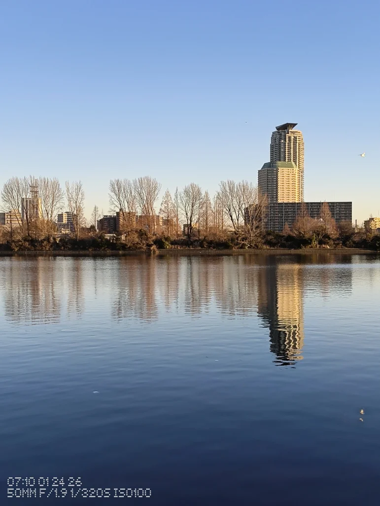 Nothing Phone (3a) Lite/カメラ:メイン(広角)2倍ズーム/焦点距離:50mm相当/内容:対岸の高層ビルを引き寄せて外壁のラインと窓の反復を強調し、水面の反射と空の階調で落ち着いた景観を描く
