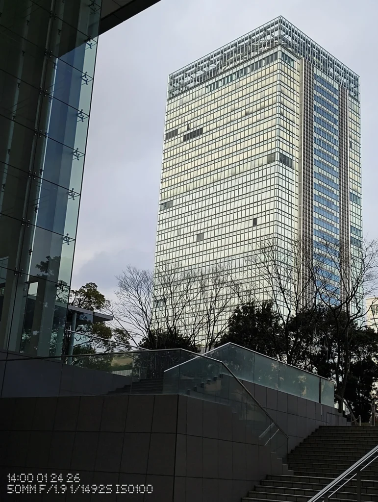 Nothing Phone (3a) Lite/カメラ:メイン(広角)2倍ズーム/焦点距離:50mm相当/内容:ガラス張りのビルと階段のある前景を組み合わせ、曇り空の下で捉えた屋外の2倍ズーム作例