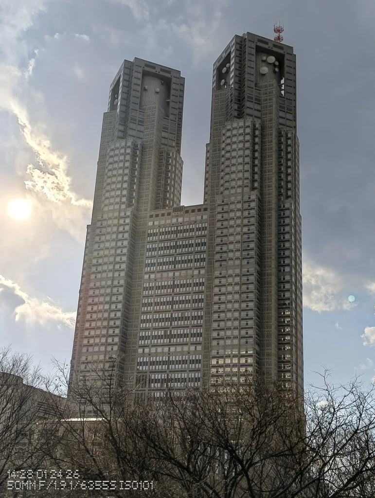 Nothing Phone (3a) Lite/カメラ:メイン(広角)2倍ズーム/焦点距離:50mm相当/内容:太陽の逆光下で双塔の高層ビルを捉え、雲と光芒が入る屋外の2倍ズーム作例