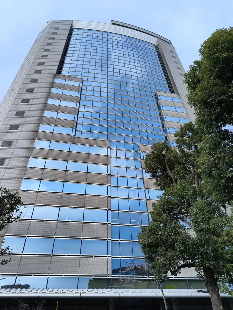 Nothing Phone (3a) Liteで撮影したガラス張り高層ビル(オリジナル)。青空の反射と樹木を写した写真