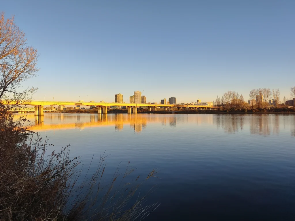 夕暮れ時の黄金色の光に包まれた橋と、鏡のように静かな川面への美しい映り込み。Redmi Note 15 Pro 5G(2億画素モード)で撮影。