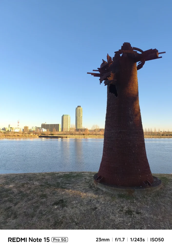 Redmi Note 15 Pro 5G メインカメラ作例。河川敷のオブジェと都市のスカイライン。明暗差のあるシーンでの黒つぶれ抑制を検証。