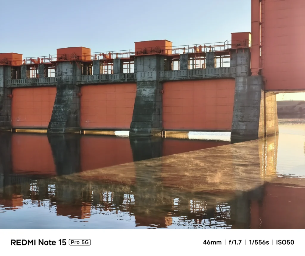 穏やかな水面に映り込む赤い水門の影と、冬の朝の光が作る反射。Redmi Note 15 Pro 5Gで撮影。