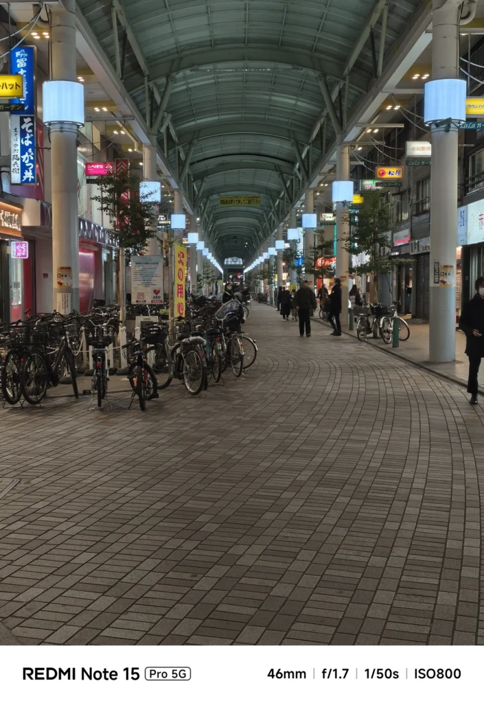 夜のアーケード商店街を望遠気味に捉えた構図。高い天井の構造と奥行きのある風景。Redmi Note 15 Pro 5G(46mm/夜景モード)で撮影。