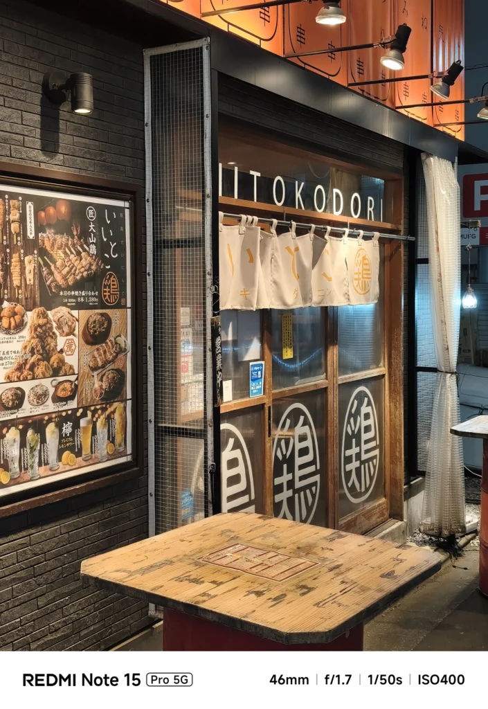 焼き鳥店「いっとく鳥」の入り口と外壁。暖色系の照明に照らされたタイルの質感。Redmi Note 15 Pro 5G(46mm/夜景モード)で撮影。