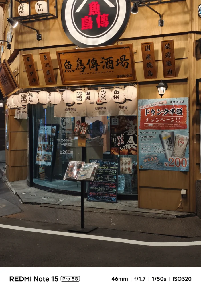 「魚鳥傳酒場」の看板とメニュー台。複雑な光源下でも文字がはっきりと読み取れる解像感。Redmi Note 15 Pro 5G(46mm/夜景モード)で撮影。