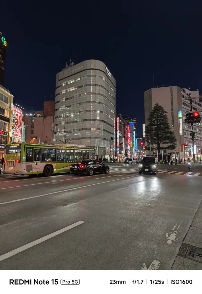夜の交差点を走る路線バスとビル明かり。濡れた路面のようなアスファルトの質感描写。Redmi Note 15 Pro 5G(23mm/夜景モード)で撮影。