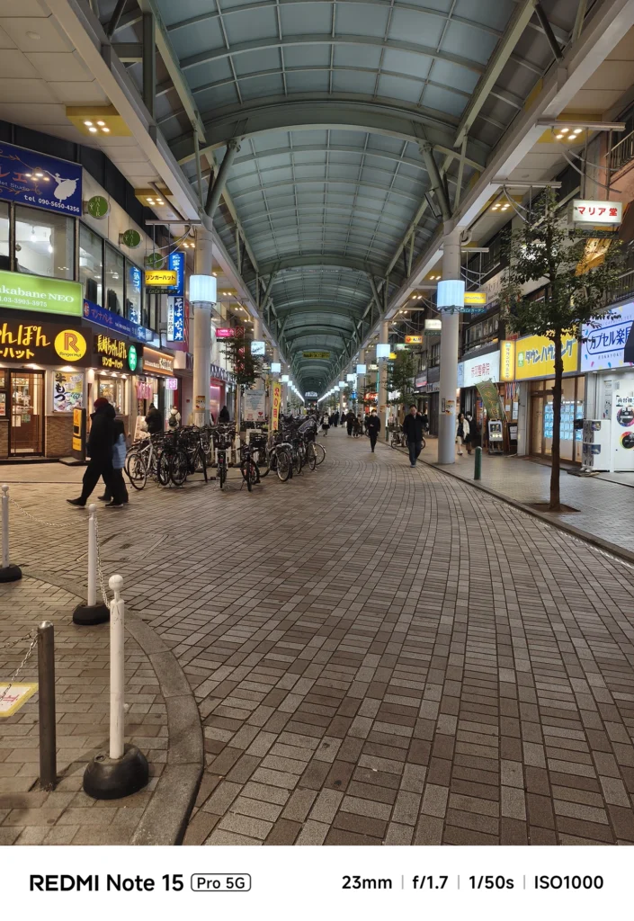 夜のアーケード商店街のパースペクティブ。高い天井の構造と店舗の照明のバランス。Redmi Note 15 Pro 5G(23mm/夜景モード)で撮影。