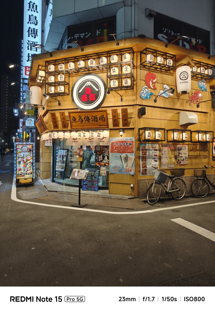 角地に建つ華やかな外観の居酒屋「魚鳥傳酒場」。提灯の質感と文字まで鮮明な夜景ショット。Redmi Note 15 Pro 5G(23mm/夜景モード)で撮影。