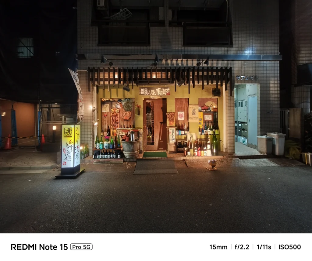 夜の路地に佇む趣ある居酒屋の店構え。並べられた一升瓶と看板の灯り。Redmi Note 15 Pro 5G(15mm/夜景モード)で撮影。