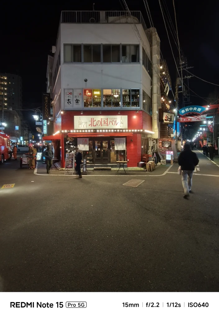 夜の交差点に建つ「北の国バル」の赤い外観。建物の全景を捉えた超広角ショット。Redmi Note 15 Pro 5G(15mm/夜景モード)で撮影。
