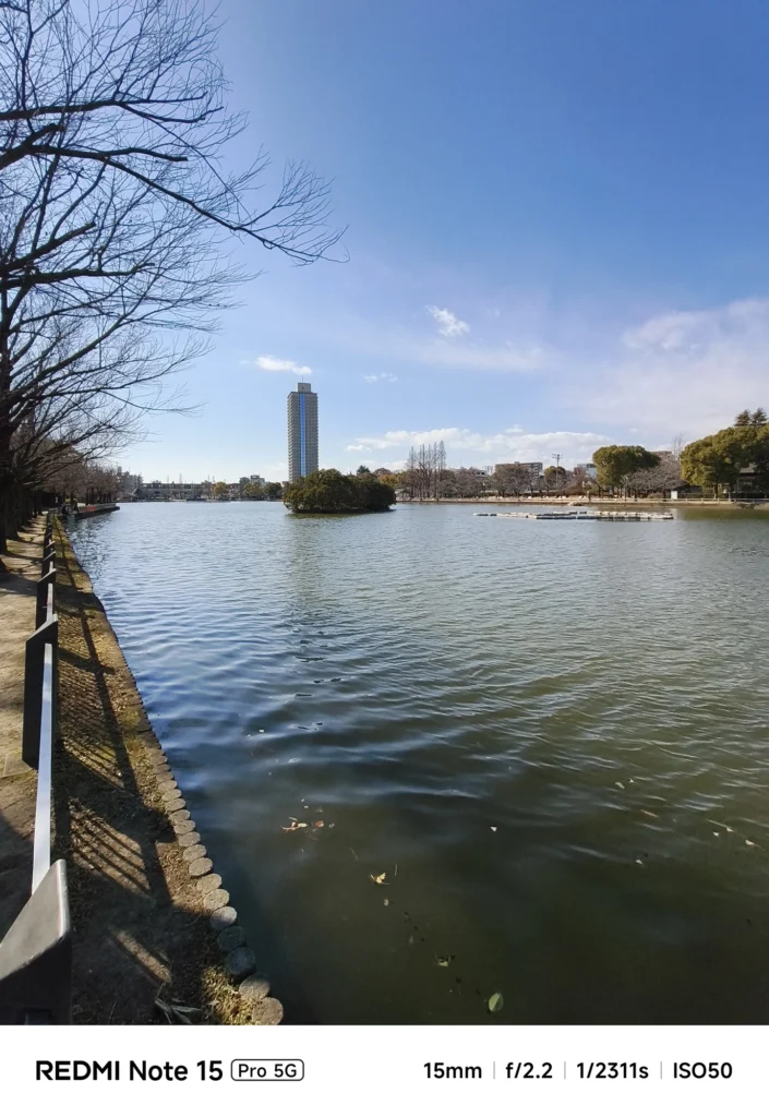 Redmi Note 15 Pro 5G 超広角カメラ作例。公園の池と遠景のビル群を15mmで広く捉えた風景写真(ISO50)。