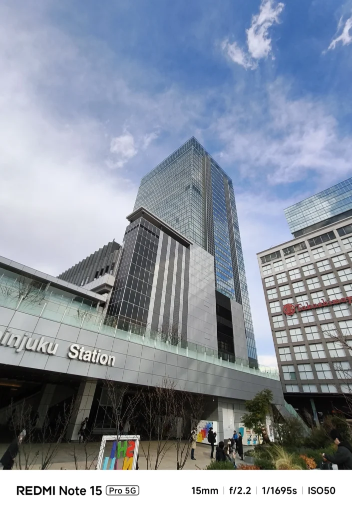 Redmi Note 15 Pro 5G 超広角カメラ(15mm)による新宿駅サザンテラス周辺の建築物と青空の作例。