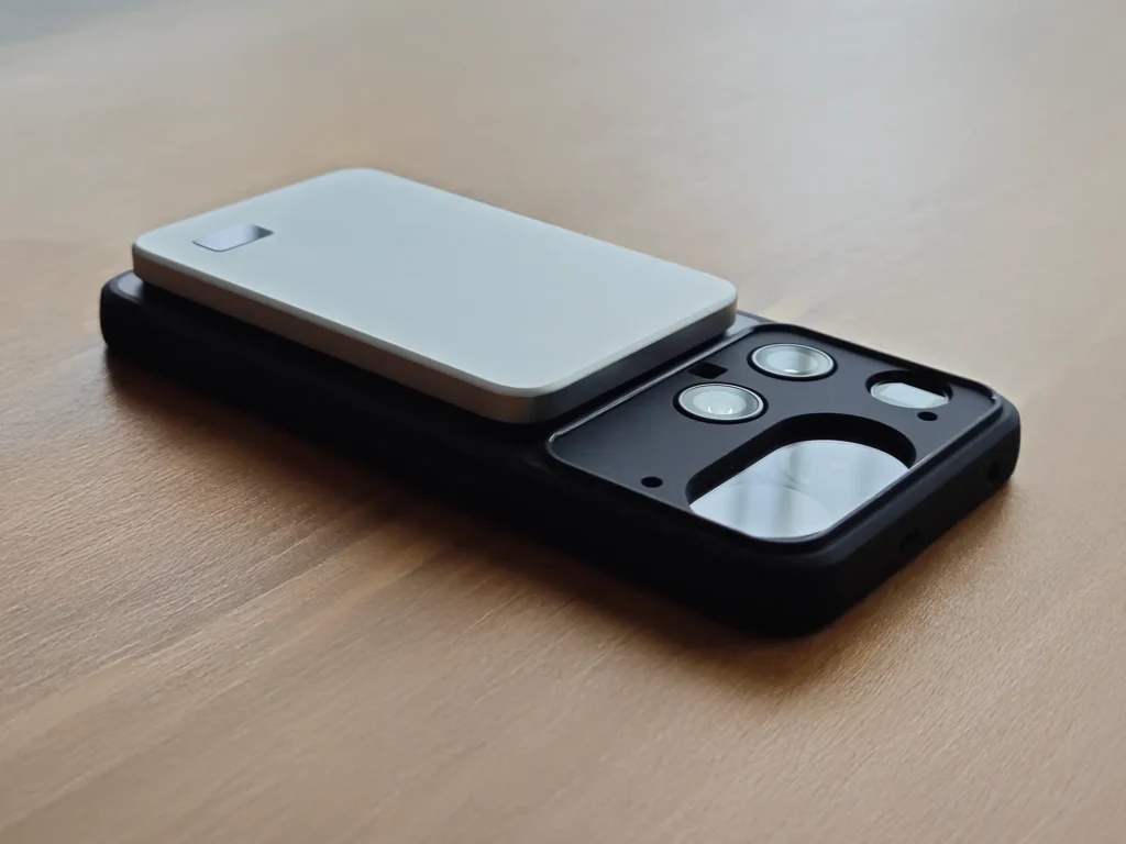 テーブルに置かれたスマホに装着中のモバイルバッテリー。カメラユニットへの干渉がなく、フラットに張り付いている側面写真