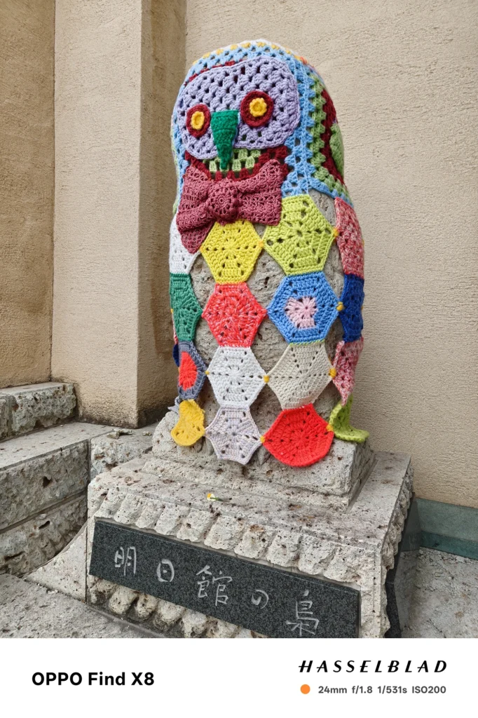Find X9（0613c1）: 編み物で覆われたフクロウの石像。23mm f/1.6の明るいレンズにより、毛糸の網目一つひとつが非常にシャープに捉えられている。