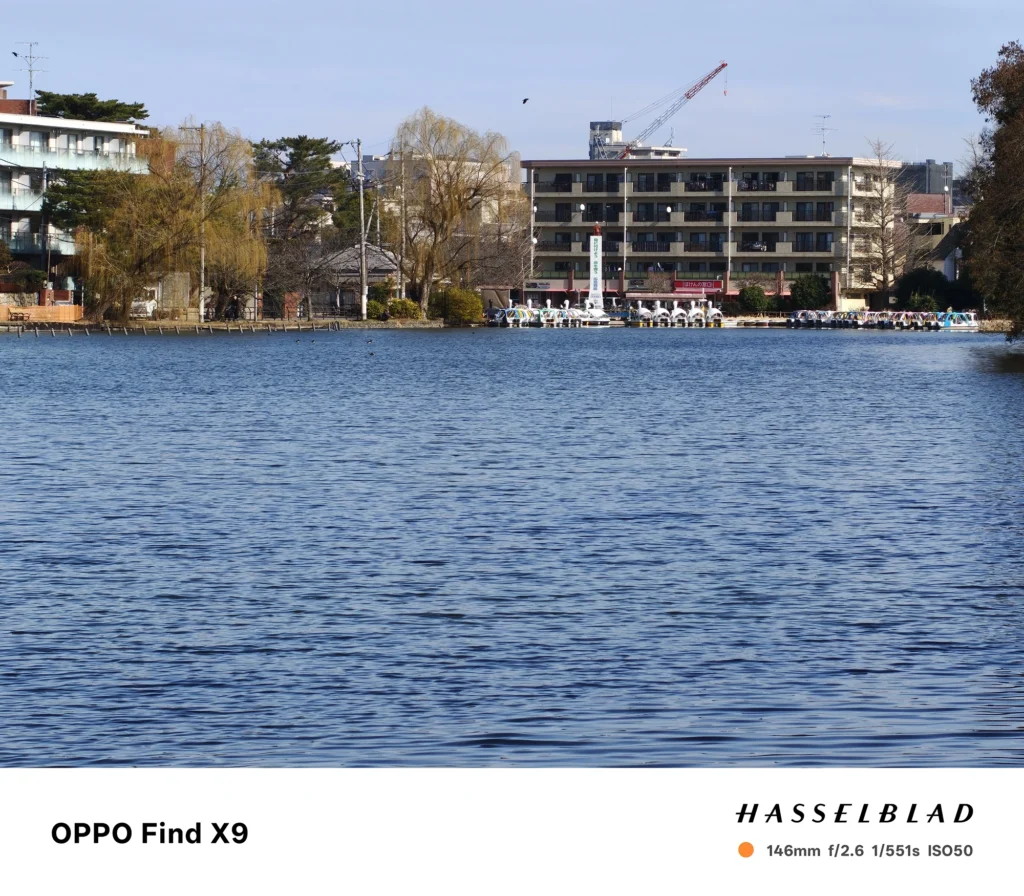 OPPO Find X9で撮影した146mm望遠の風景写真。湖面の波紋を前景に、対岸の建物と桟橋（ボート乗り場）付近を引き寄せて写している。
