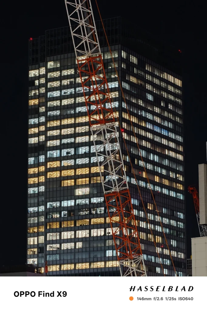 端末名：Find X9／カメラ：望遠／焦点距離：146mm相当／内容：高層ビルの窓明かりと斜めに走るクレーンを望遠で引き寄せ、点光源が密集する夜景を圧縮効果でシャープに見せる