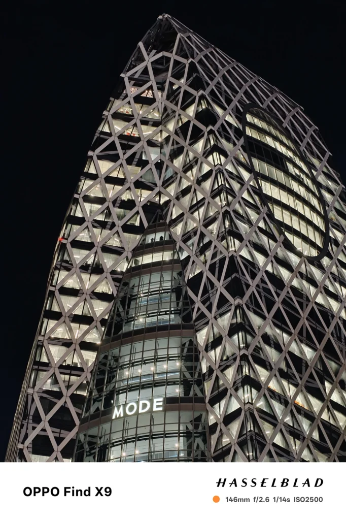 端末名：Find X9／カメラ：望遠／焦点距離：146mm相当／内容：格子状の高層ビルと窓明かりを望遠で引き寄せ、黒い夜空に直線と点光源が圧縮されるシャープな都市夜景