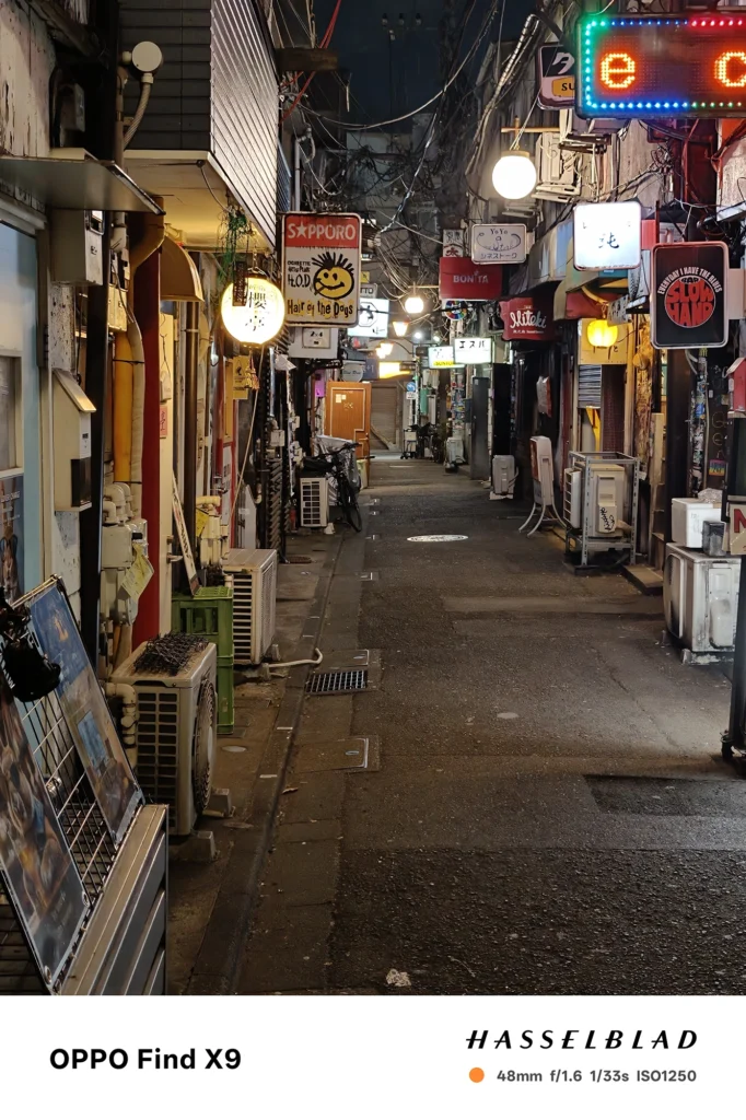 端末名：Find X9／カメラ：メイン（広角）2倍ズーム／焦点距離：48mm相当／内容：大通りの先にそびえる高層ビルを2倍ズームで引き寄せ、窓明かりの点光源と道路の白線が伸びる都市夜景