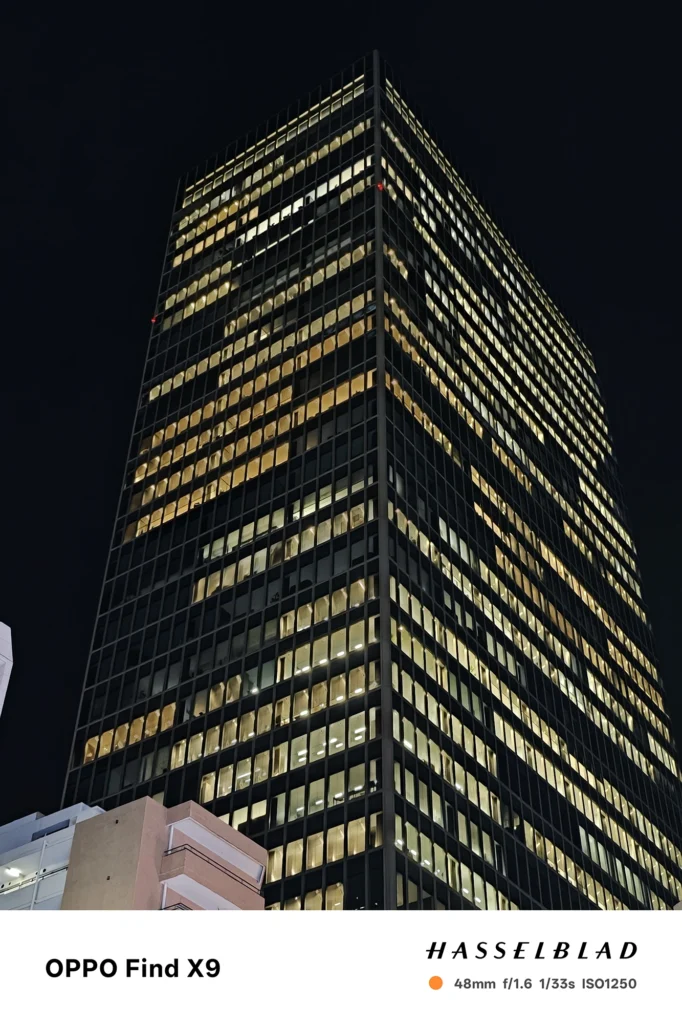 端末名：Find X9／カメラ：メイン（広角）2倍ズーム／焦点距離：48mm相当／内容：オフィスビルの窓明かりを2倍ズームで引き寄せ、点光源が格子状に並ぶ外観と黒い夜空が対比する夜景