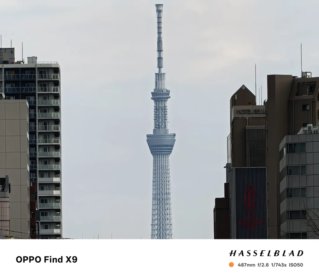 487mm（スカイツリー）: OPPO Find X9で撮影した487mm相当の超望遠写真。ビルの間から東京スカイツリーを極端に引き寄せた遠景ショット。