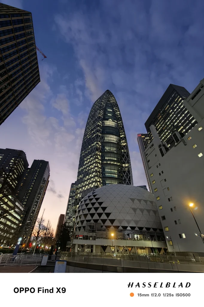 端末名：Find X9／カメラ：超広角／焦点距離：15mm相当／内容：夕暮れの高層ビルとドーム状建築を見上げた構図で、窓明かりと空の階調が残る夜景