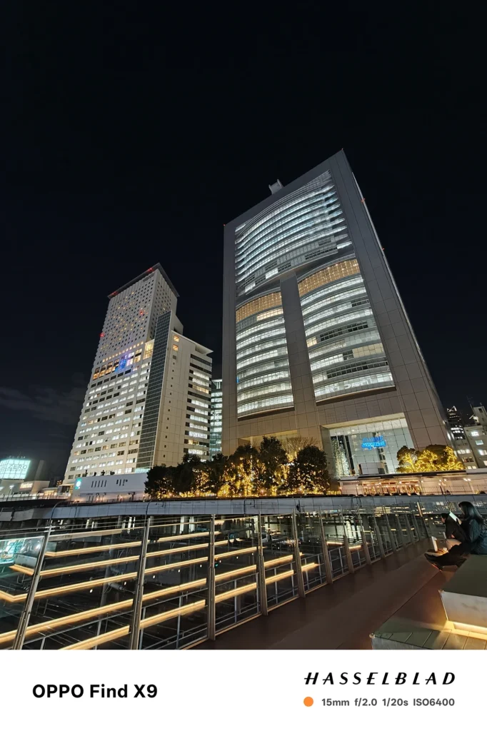 端末名：Find X9／カメラ：超広角／焦点距離：15mm相当／内容：駅前広場と高層ビル群を広角で捉え、植栽のイルミとビルの窓明かりが映える夜景