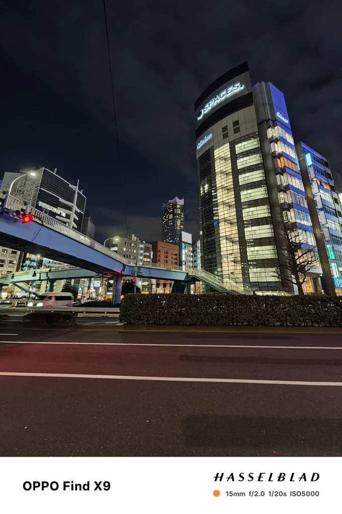 端末名：Find X9／カメラ：超広角／焦点距離：15mm相当／内容：高架歩道橋と看板のある交差点を広く写し、ネオンと室内光が混ざる夜の街並み