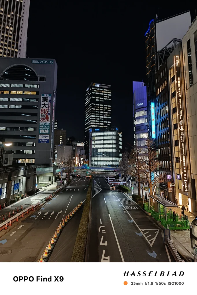 Find X9／カメラ：メイン（広角）／焦点距離：確認不能（mm相当）mm相当／内容：ネオン看板が並ぶ夜の繁華街通りを広く写し、車のライトと街灯が路面の反射を強調する賑やかな夜景