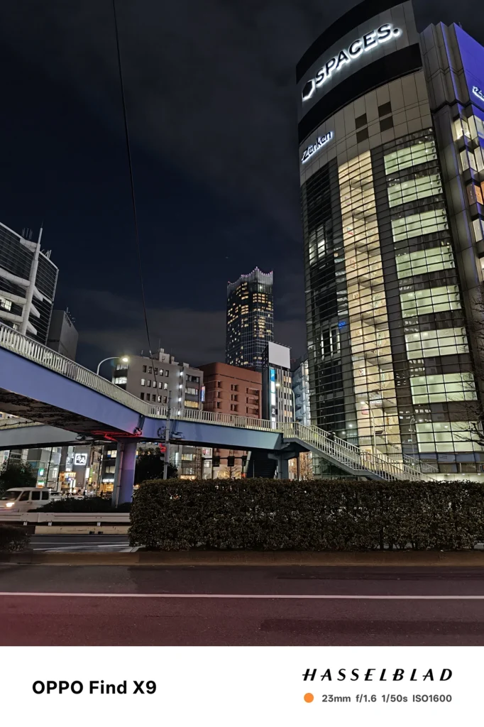 端末名：Find X9／カメラ：メイン（広角）／焦点距離：確認不能（mm相当）mm相当／内容：歩道橋とビル群の夜景を見上げ、窓明かりと街灯が冷えた空に映える落ち着いた都市の雰囲気