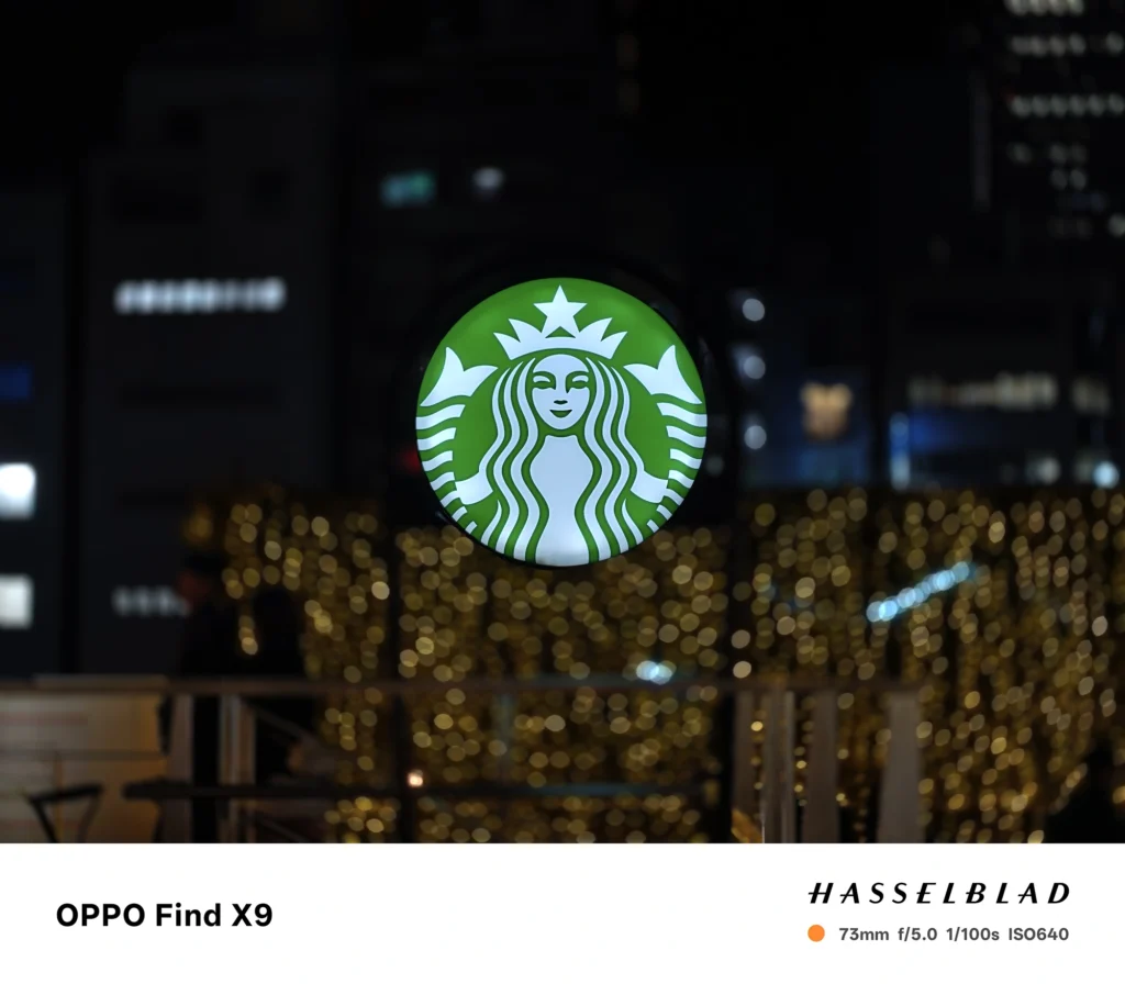 夜景のスターバックス看板を73mmで撮影（OPPO Find X9）。イルミネーションを大きな玉ボケにした作例。