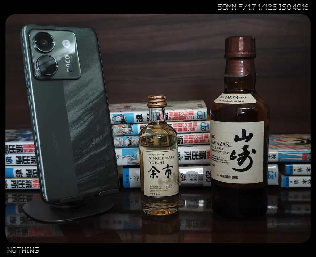 Nothing Phone 3でスマホ、ウイスキーボトル、漫画本を暗めの屋内で2倍撮影した作例