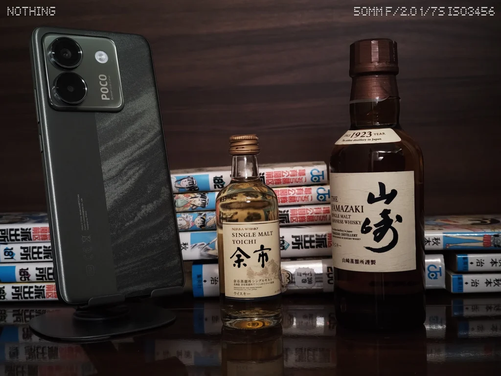 Nothing Phone 3aでスマホ、ウイスキーボトル、漫画本を暗めの屋内で2倍撮影した作例