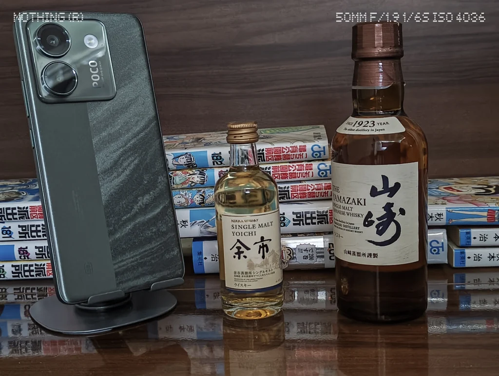 Nothing Phone 3a Liteでスマホ、ウイスキーボトル、漫画本を暗めの屋内で2倍撮影した作例